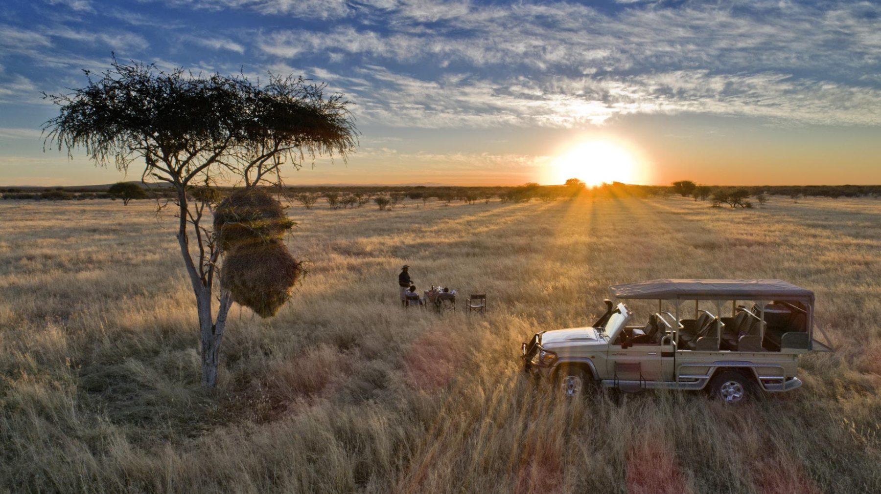 Safari vehicle at sunset on the open plain