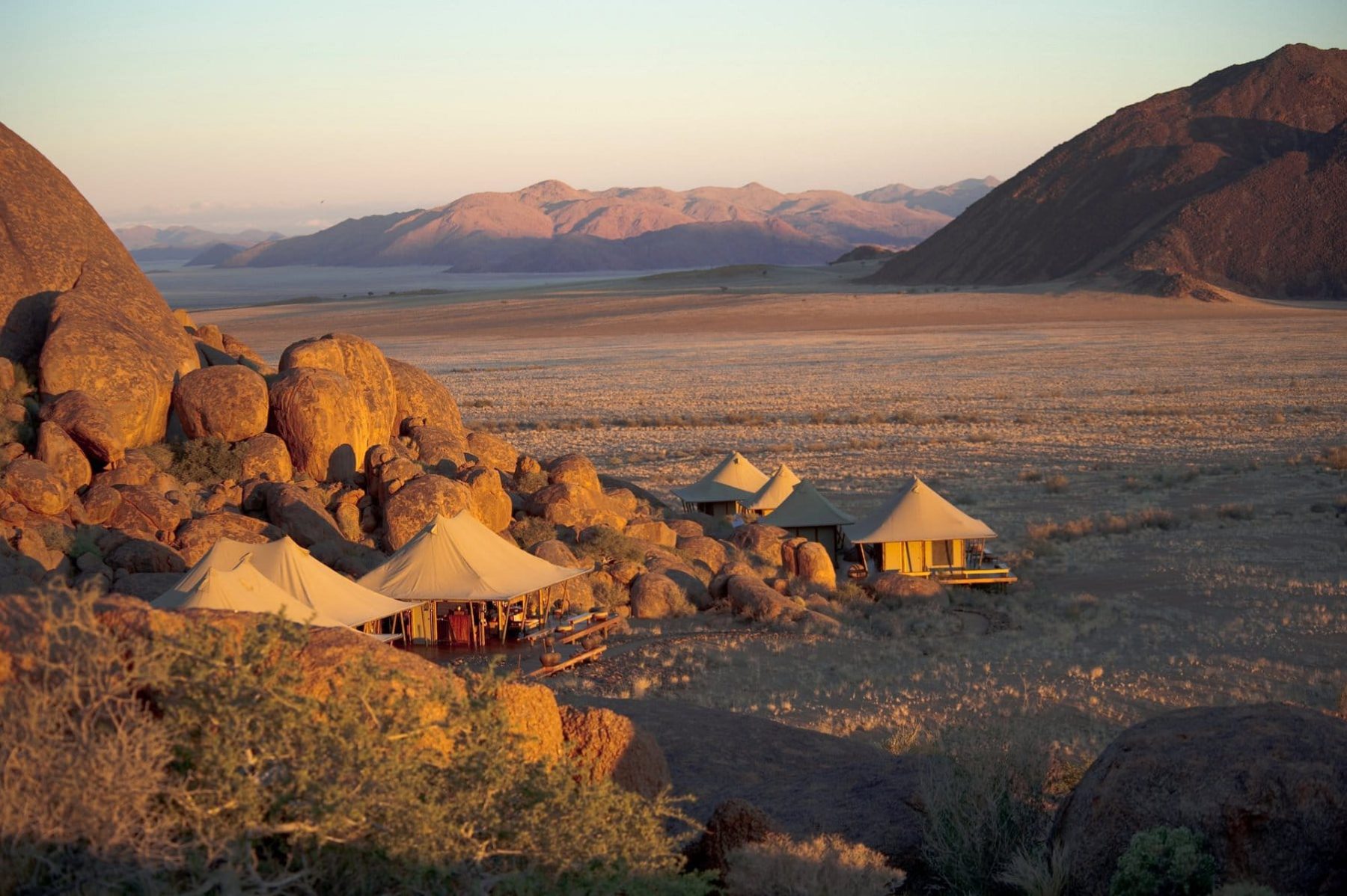 Tented camp among red rocks at sunset