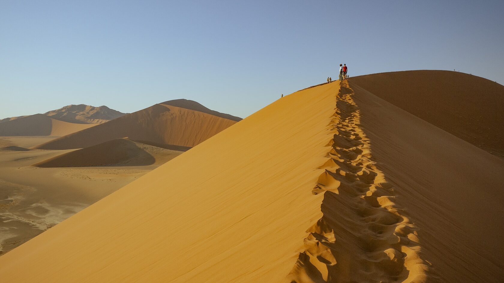 Walkers on the crest of a red dune