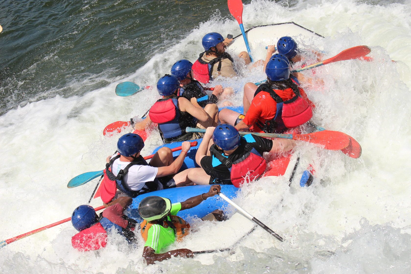 Rafting team paddling through rapids